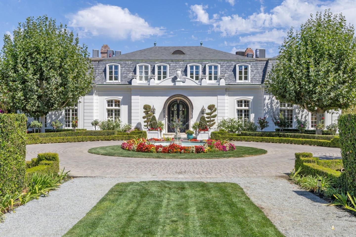 French-style estate at 320 Harcross Road in Woodside, California, with a circular gravel drive, fountain and clipped hedges