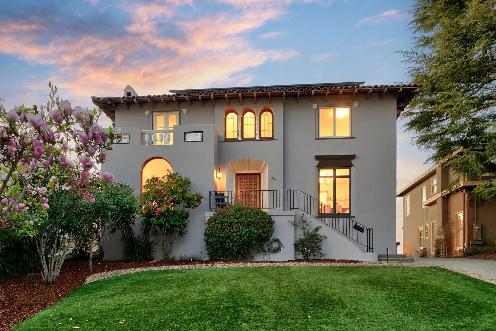 662 Calmar Avenue, a 1926 Spanish-style home in Crocker Highlands, Oakland, at dusk with a magnolia in bloom